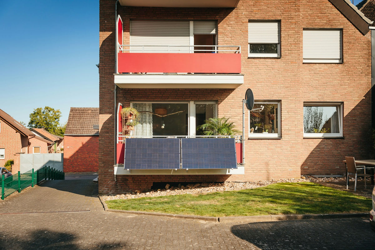 Balkon mit Solarmodulen an einem Backsteingebäude